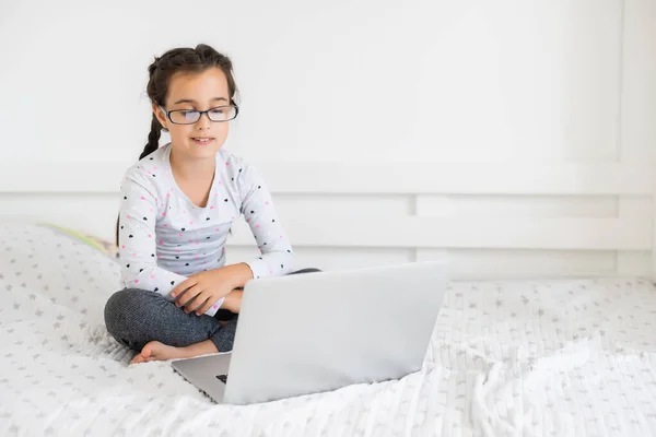 Gelukkig klein meisje thuis werken met een laptop — Stockfoto