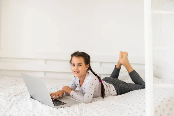 Klein meisje studeren online met behulp van haar laptop thuis — Stockfoto