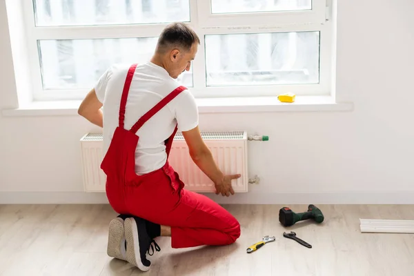 Un hombre corta una tubería con una sierra circular, chispas voladoras, reemplazo del radiador en el apartamento, trabajos de plomería — Foto de Stock