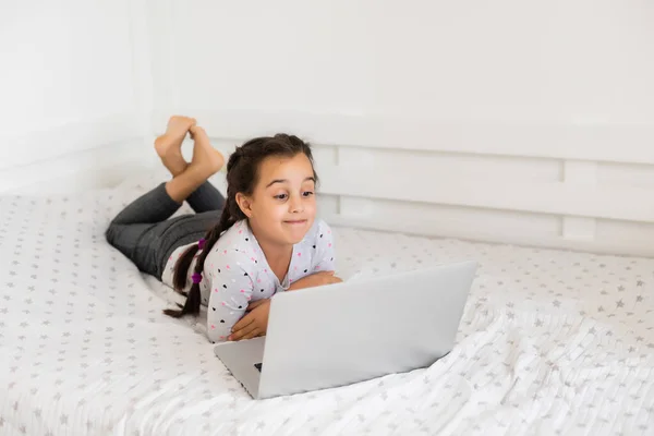 Gelukkig klein meisje thuis werken met een laptop — Stockfoto