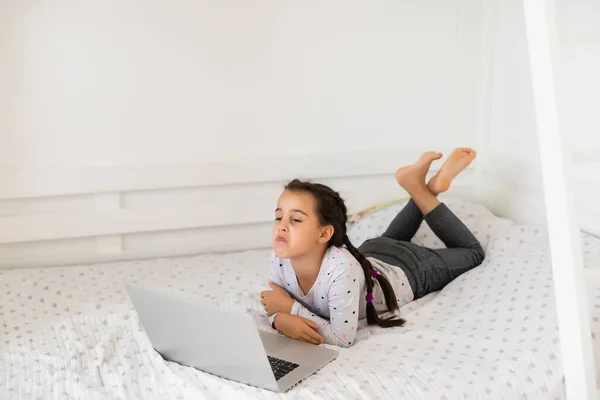 Klein meisje studeren online met behulp van haar laptop thuis — Stockfoto