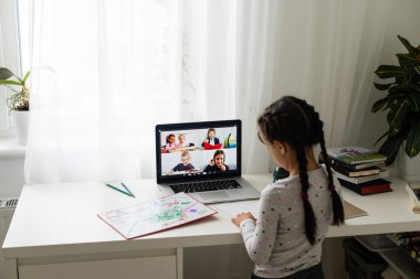 Evde bilgisayarını kullanarak internetten ders çalışan küçük bir kız.