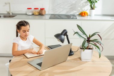 Küçük kız Studen evde dizüstü bilgisayarla online ders çalışıyor. Covid-19 koronavirüs. Sosyal uzaklık, evde eğitim..