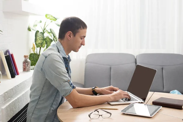 Heureux jeune homme souriant, car il travaille sur son ordinateur portable pour faire toutes ses affaires tôt le matin — Photo