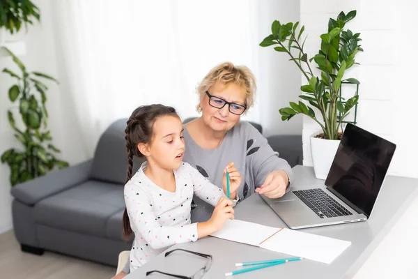 Roztomilé a šťastný holčička pomocí notebooku s babičkou, studuje prostřednictvím on-line e-learningového systému. — Stock fotografie