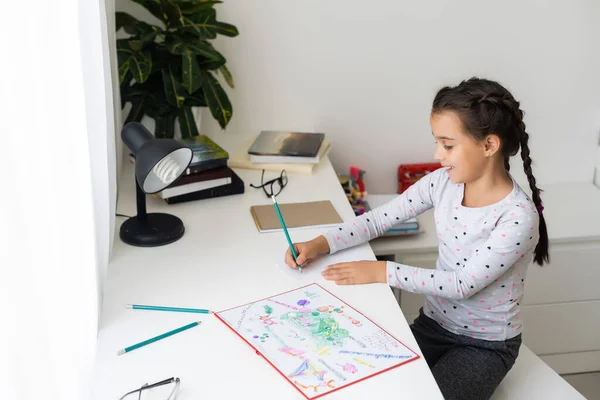 Una bambina che fa i compiti di scrittura e lettura a casa — Foto Stock