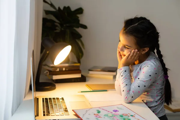 Liten flicka studerar online med hjälp av sin bärbara dator hemma — Stockfoto