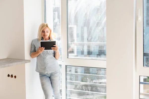 woman with tablet looking for cleaning to wash dirty window
