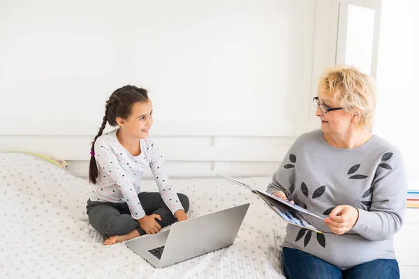 Ragazzina carina e felice utilizzando il computer portatile con la nonna, studiando attraverso il sistema di e-learning online. — Foto Stock