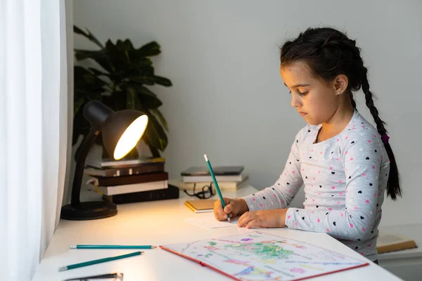 Una bambina che fa i compiti di scrittura e lettura a casa — Foto Stock