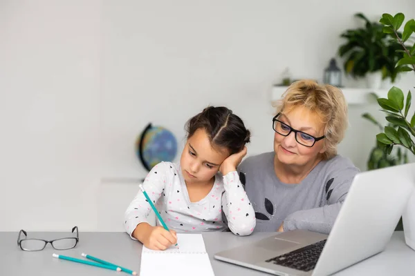귀엽고 행복 한 어린 아이가 할머니와 함께 노트북 컴퓨터를 사용하며 온라인 전자 학습 시스템을 공부하고 있습니다.. — 스톡 사진