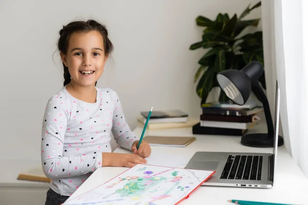 Gelukkig klein meisje thuis werken met een laptop — Stockfoto