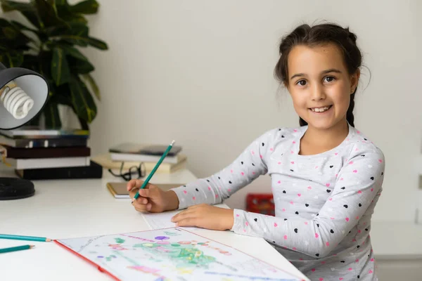 Küçük kız gülüyor, oyun masasında renkli kalemler çiziyor. — Stok fotoğraf