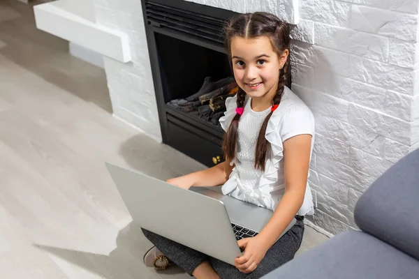 Foto do estudo positivo da menina criança laptop uso remoto tem aula de comunicação on-line com relatório de escrita tutor em casa dentro de casa — Fotografia de Stock