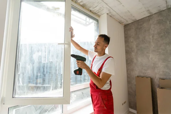 Master with a screwdriver sets fittings on the window — Stock Photo, Image