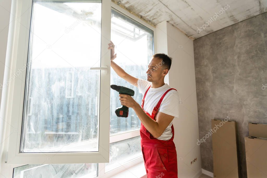 master with a screwdriver sets fittings on the window
