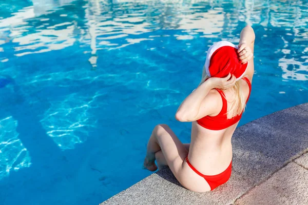 Mulher bonita em chapéu de Santa perto da piscina — Fotografia de Stock