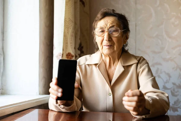 Жінка старша зі своїм смартфоном, дуже стара жінка показує свій телефон — стокове фото