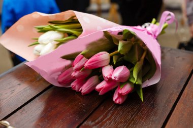Beyaz ve pembe lale buketleri. Tahta bir masanın üzerinde iki çiçek buketi var. Tebrik kartı için temel fikir. Bahar geldi.