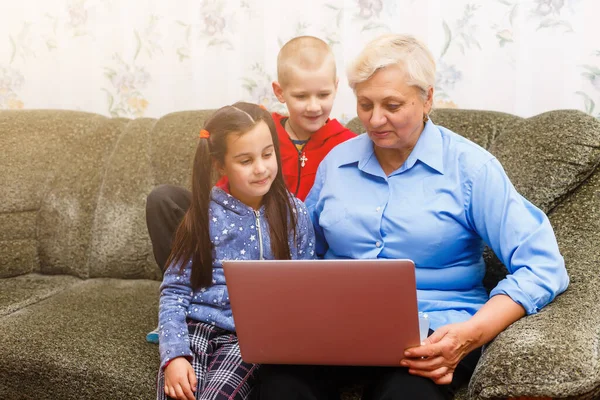 Nonna con nipoti che utilizzano il computer portatile a casa — Foto Stock