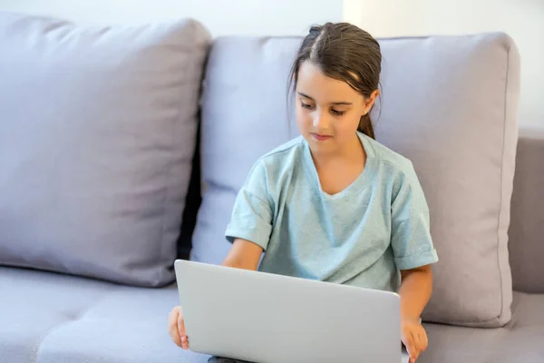 Ragazzina carina che usa il portatile a casa. Istruzione, studio online, studio a casa, apprendimento a distanza, scolaretta concetto di stile di vita dei bambini — Foto Stock