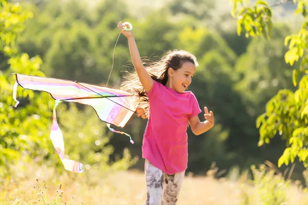 Kleines Mädchen läuft mit einem Drachen im Freien — Stockfoto