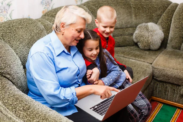 Grandmother with grandchildren using laptop at home