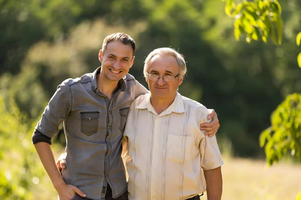 Vater und Sohn blicken im Garten in die Kamera — Stockfoto