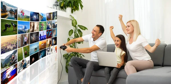 Familia joven divirtiéndose jugando videojuegos en una pantalla enorme en casa — Foto de Stock
