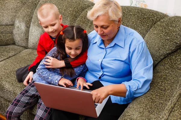 Nonna con nipoti che utilizzano il computer portatile a casa — Foto Stock