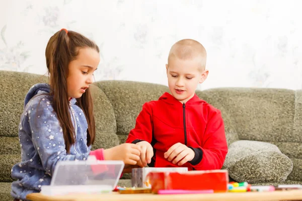 La niñita y el niño se concentran y trabajan juntos. niño y niña aprenden y juegan juntos en la mesa. A los niños les gusta escribir a mano. Amistad — Foto de Stock