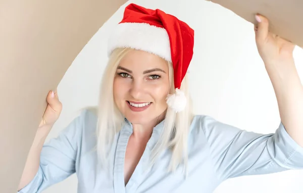 Christmas, delivery and winter holidays concept - happy young woman in santa helper hat looking into open gift box — Stock Photo, Image