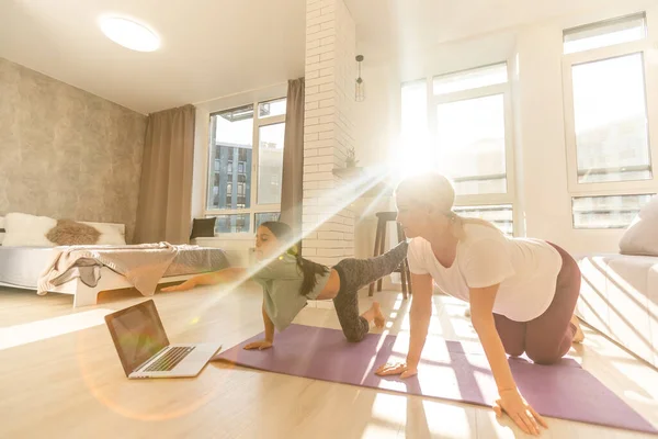 Madre e hija hacen ejercicio de yoga en línea con el ordenador portátil en casa — Foto de Stock