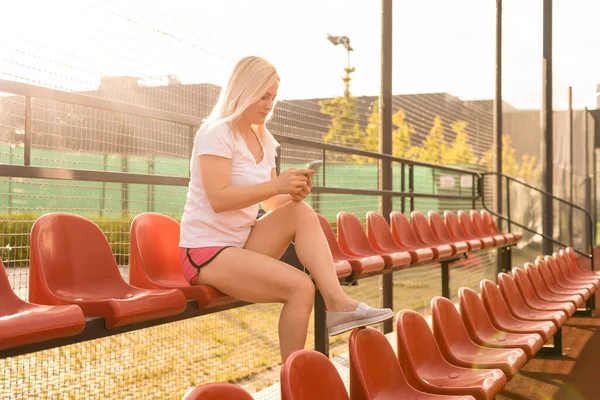 Молодая женщина сидит одна на трибунах стадиона — стоковое фото
