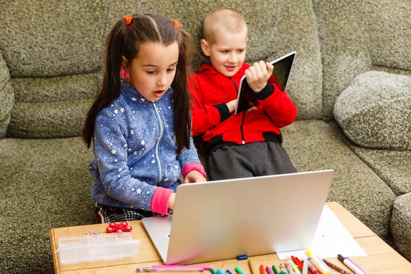 Due bei bambini sorridenti felici carini, un ragazzo e una ragazza, usano il computer portatile per l'apprendimento a distanza o l'intrattenimento. — Foto Stock