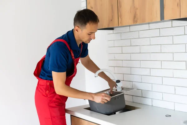 Klempner bringt Silikondichtmittel zum Einbau einer Küchenspüle — Stockfoto