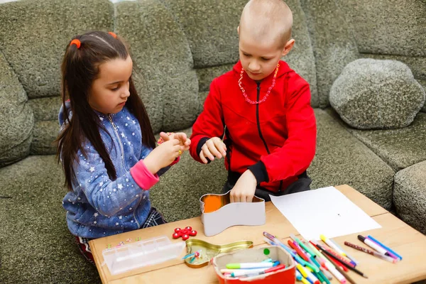 La niñita y el niño se concentran y trabajan juntos. niño y niña aprenden y juegan juntos en la mesa. A los niños les gusta escribir a mano. Amistad — Foto de Stock