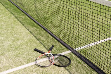 Tenis raketi ve yeni boyanmış tenis kortunda yeni bir tenis topu.