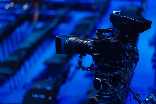 Professional camcorder, video camera, black silhouette of camera on blue background, close up