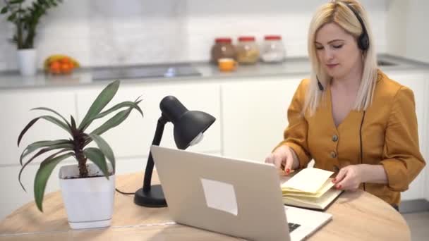 Kobieta nosi słuchawki wideo dzwoniąc do odległego pacjenta na laptopie. rozmawianie z klientem za pomocą wirtualnego czatu — Wideo stockowe