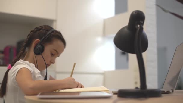 Милая маленькая девочка использует ноутбук дома. онлайн-обучение на дому — стоковое видео