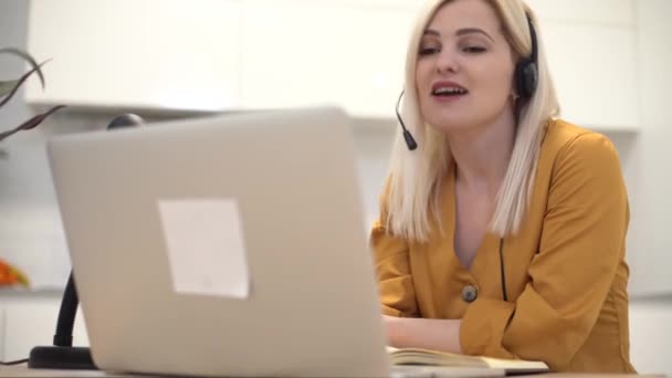 Kobieta nosi słuchawki wideo dzwoniąc do odległego pacjenta na laptopie. rozmawianie z klientem za pomocą wirtualnego czatu — Wideo stockowe