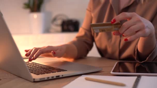 Online shopping, e-commerce, sale, consumerism, electronic payment, technology concept. Woman using laptop computer keyboard, holding credit card, buying goods or ordering online - close up side view — Stock Video
