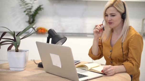 Kobieta w słuchawkach komunikuje się przez połączenie wideo na laptopie — Wideo stockowe