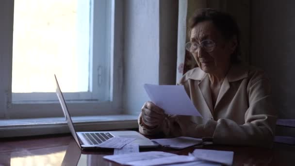 Een oudere vrouw belt thuis met een laptop. COVID 19 Online chat assistenten — Stockvideo
