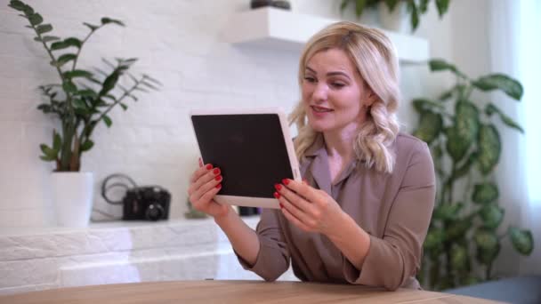 Freelance zakelijke vrouwen casual kleding met behulp van tablet werken oproep video conferentie met de klant op de werkplek in de woonkamer thuis. gelukkig jong meisje ontspannen zitten op bureau doen baan in internet. — Stockvideo