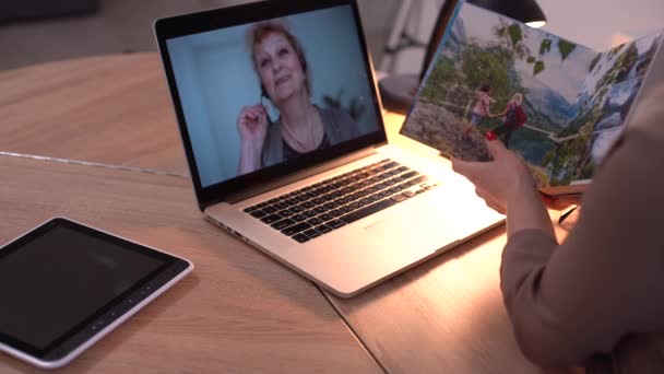 Žena drží a prezentuje fotoknihu v blízkosti notebooku — Stock video