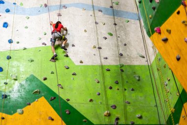 Küçük kız kaya duvarına tırmanıyor.