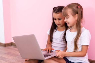 Pembe arka planda izole edilmiş beyaz tişört gösteren küçük kızlar. Çocukluk yaşam tarzı konsepti. Kopyalama alanı oluşturun. İşaret parmağı bir yana