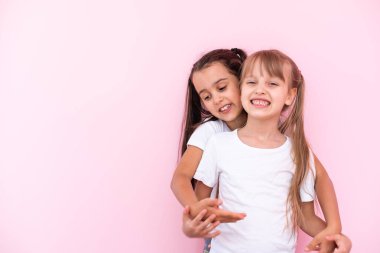 İki küçük kız. Pembe bir arka planda izole edilmiş en iyi arkadaşlar.